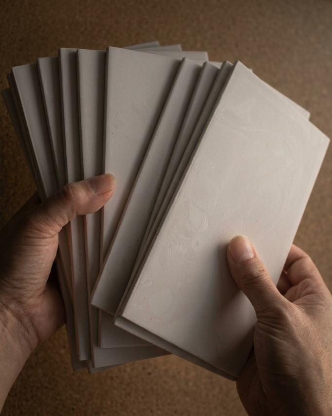hands holding pre fired tiles