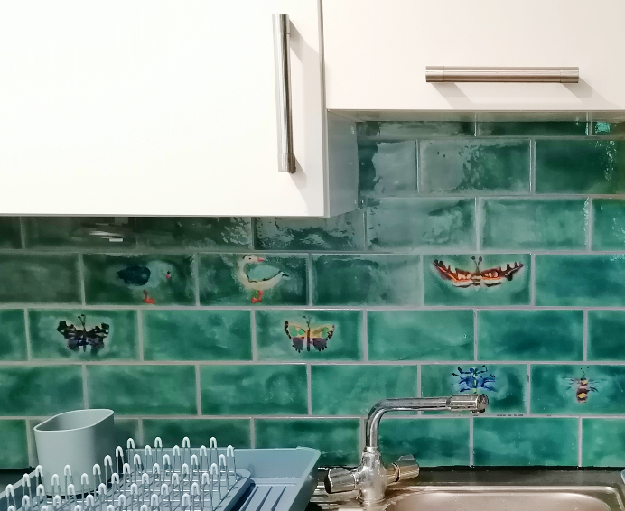Hand-painted insect, butterfly and bird tiles in a kitchen splashback